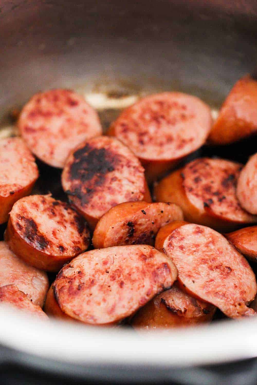 A large pot of sliced and seared smoked sausage pieces for smoked sausage stew. 