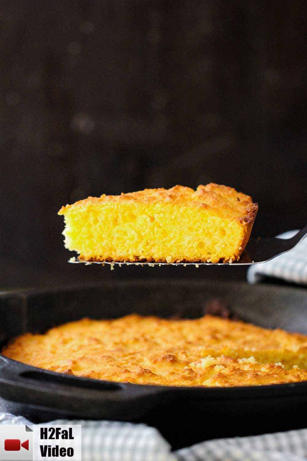 A spatula rising out of a cast iron skillet of homemade cornbread. 