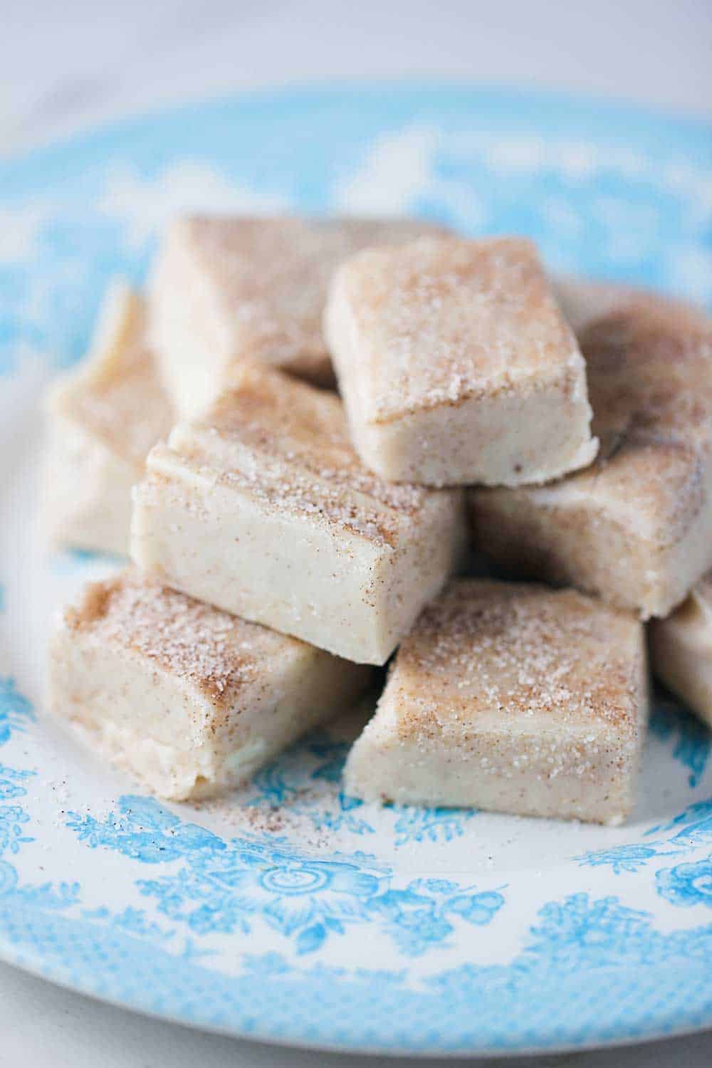 Square pieces of snickerdoodle fudge on a blue patterned plate. 