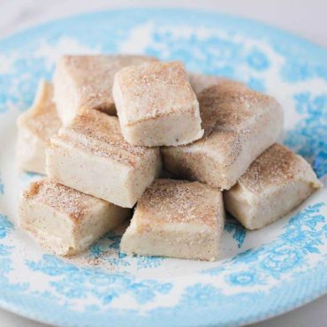 Square pieces of snickerdoodle fudge on a blue patterned plate.