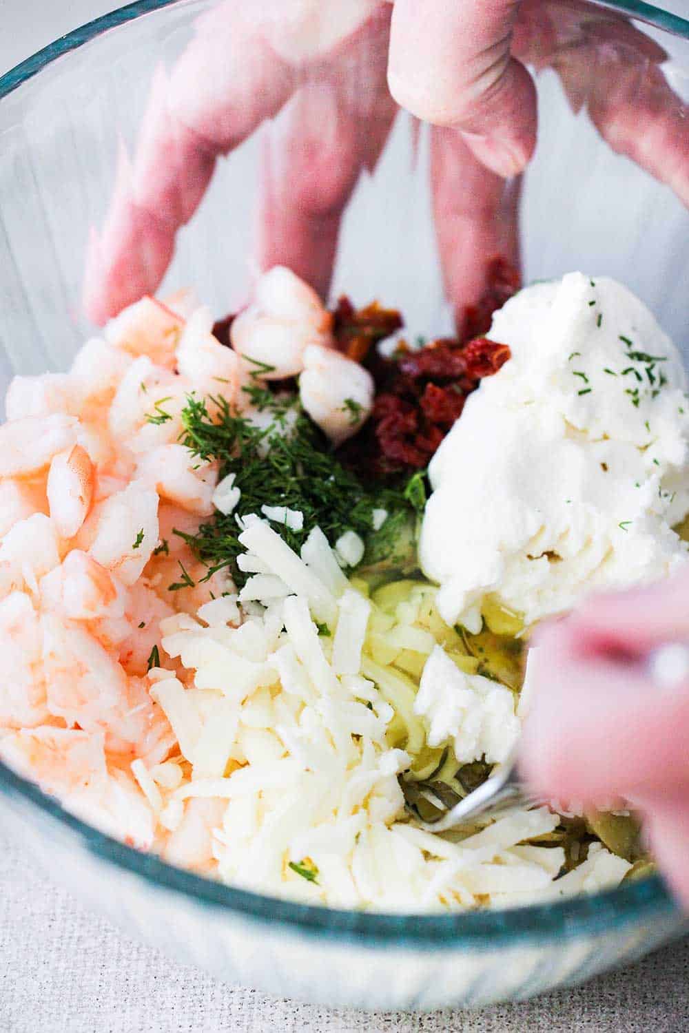 A hand holding a bowl of ingredients for air fryer phyllo triangles. 