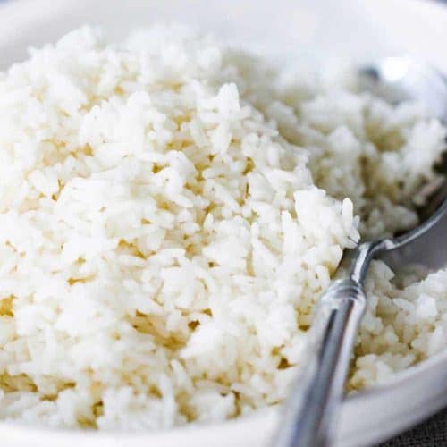 A white bowl of perfect steamed rice with a spoon in it.