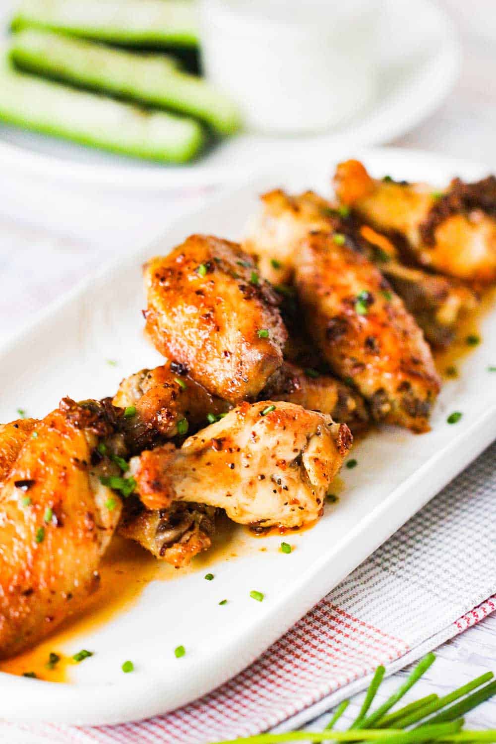 A white platter of best-ever baked hot wings sprinkled with snipped chives. 