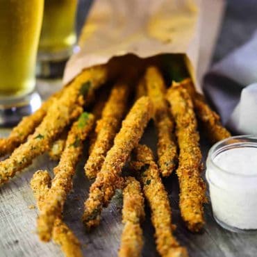 A pile of fried asparagus stalks pouring out of a paper bag.