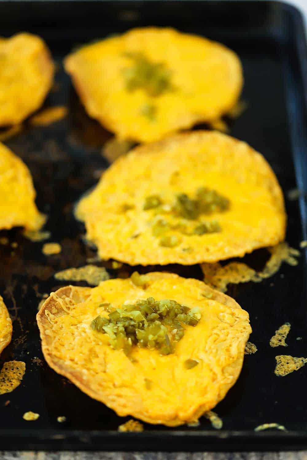 A view of three baked classic nachos on a baking sheet. 