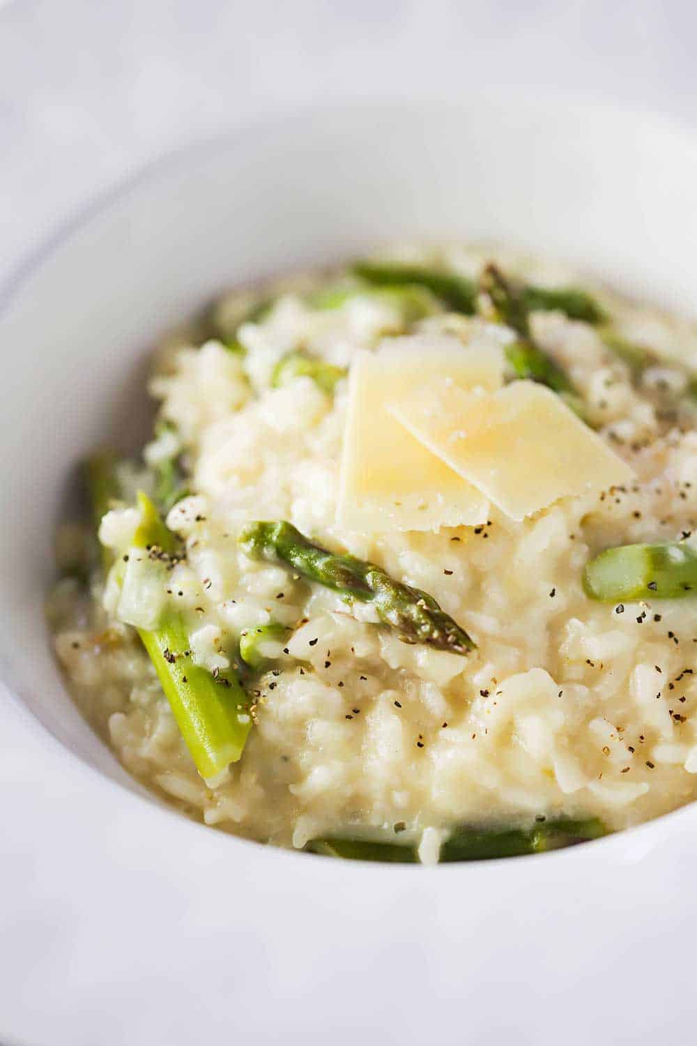 A close-up view a large white bowl filled with slow cooker asparagus risotto. 