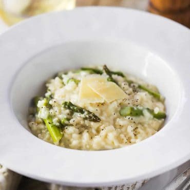 A close-up view a large white bowl filled with slow cooker asparagus risotto.