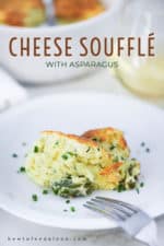 A white plate filled with a serving of cheese soufflé with snipped chives sprinkled on it and fork nearby.