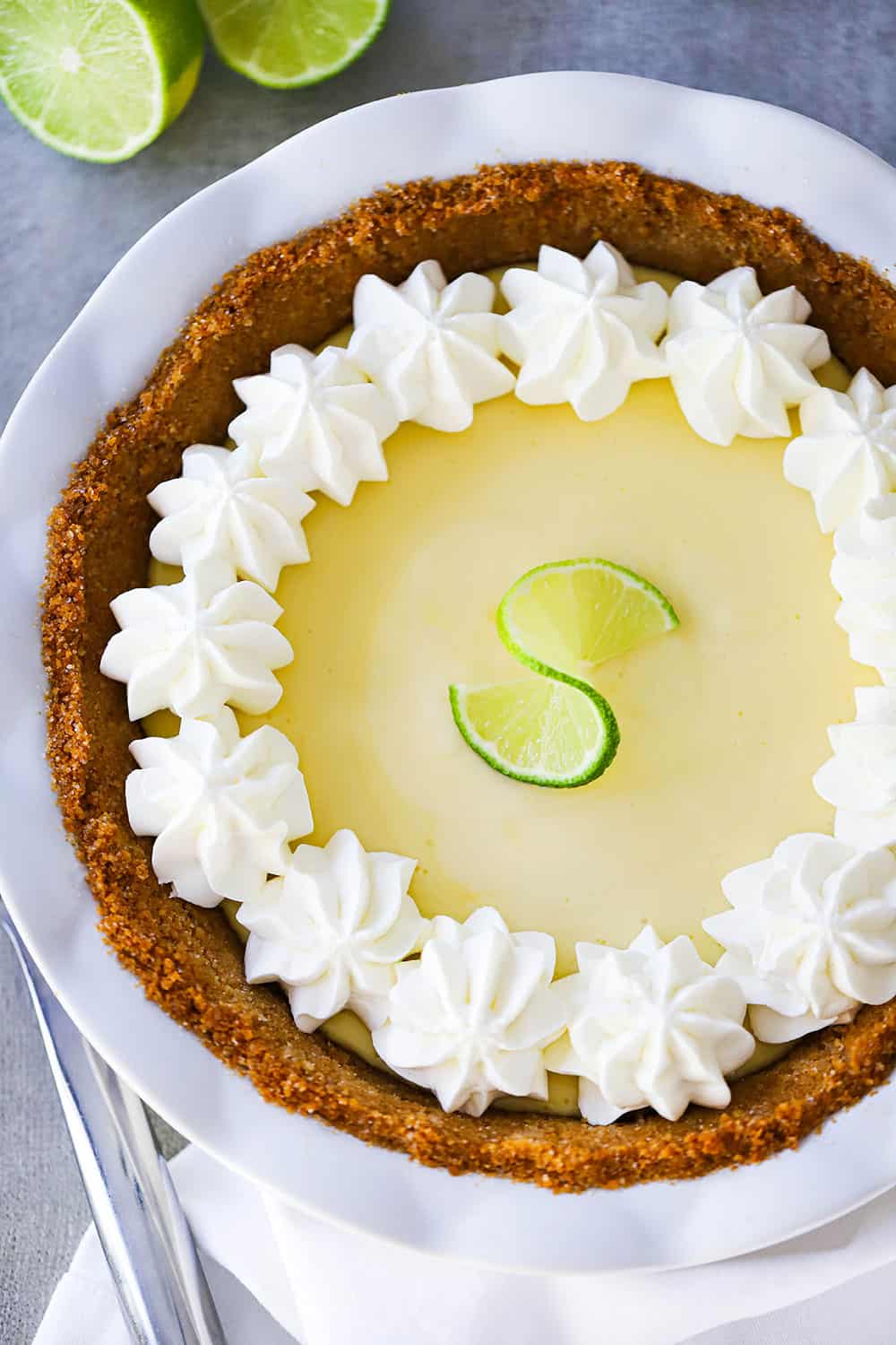 An overhead view of a key lime pie with whipped cream puffs along the edge of the crust.