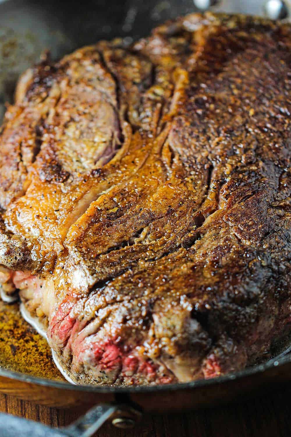 A close-up view of a 3 lb chuck roast that has been seared on both sides in a Dutch oven. 