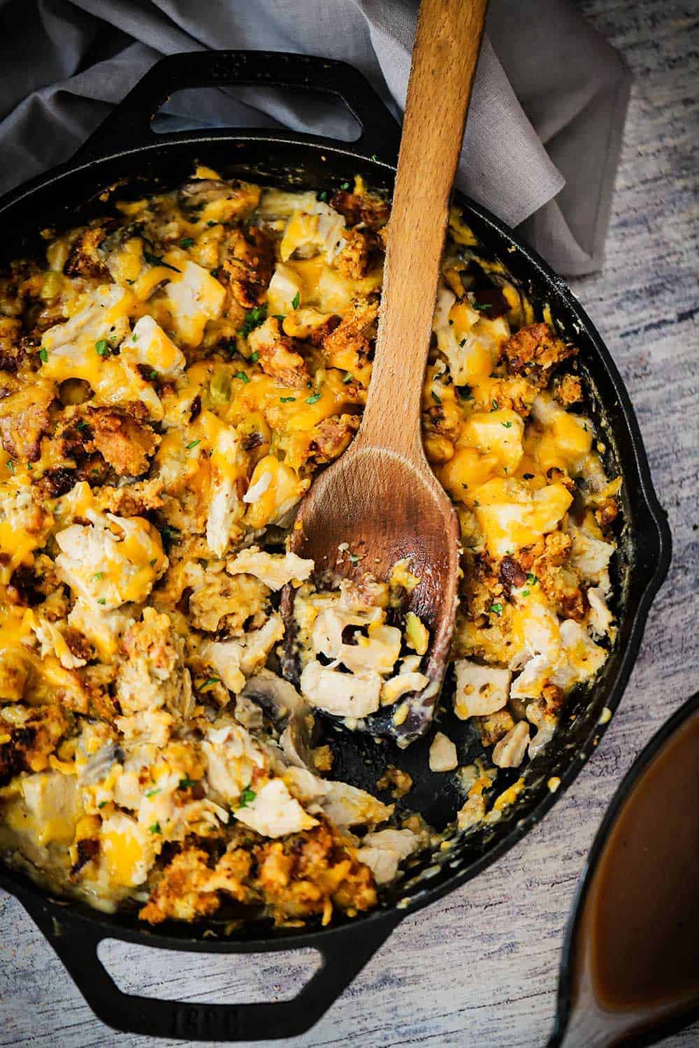 A large black cast-iron skillet filled with turkey and stuffing dressing with some of the food scooped out.