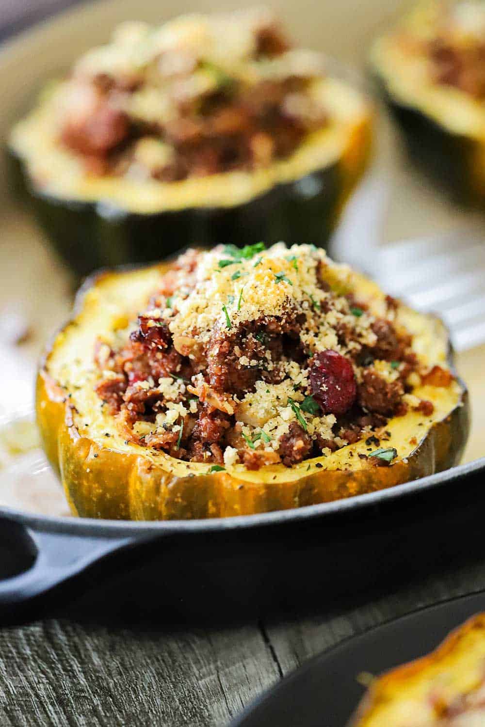 A acorn squash stuffed with a holiday stuffing in a baking dish. 