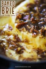 Baked brie with praline sauce in an oval baking dish.