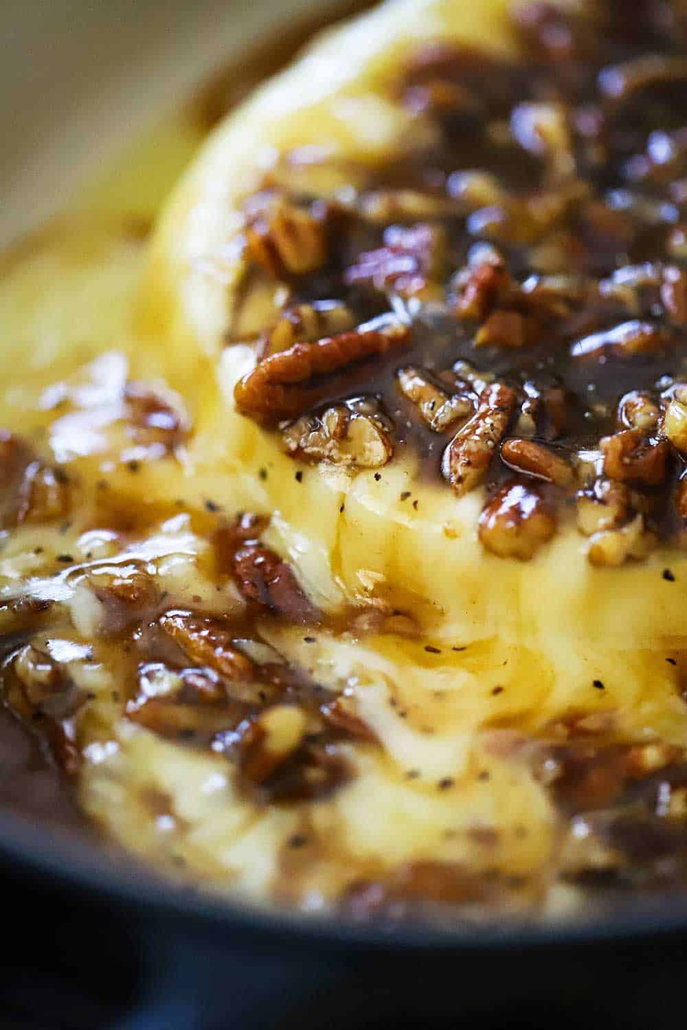 Baked brie with praline sauce in an oval baking dish. 