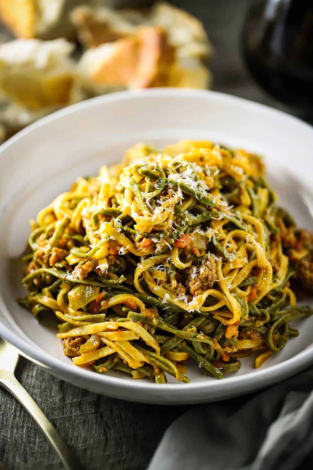 A white individual serving bowl filled with fettuccine with creamy sausage sauce.