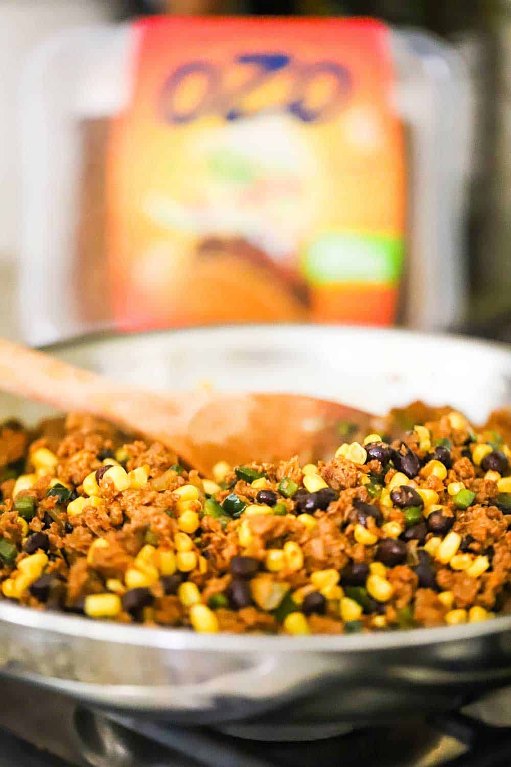 A stainless steel skillet filled with ground plant-based protein and black beans and corn. 