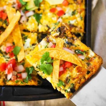 A slice of a Mexican frittata being lifted out of a sheet pan of the dish.