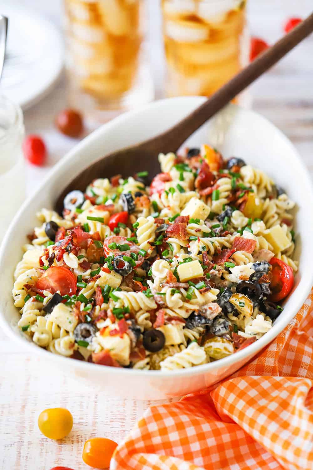 An oval white serving bowl filled with cheddar bacon Ranch pasta salad. 