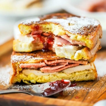 A Monte Cristo sandwich that has been sliced in half and then stacked, with a smear of preserves in the middle and a bite taken out.