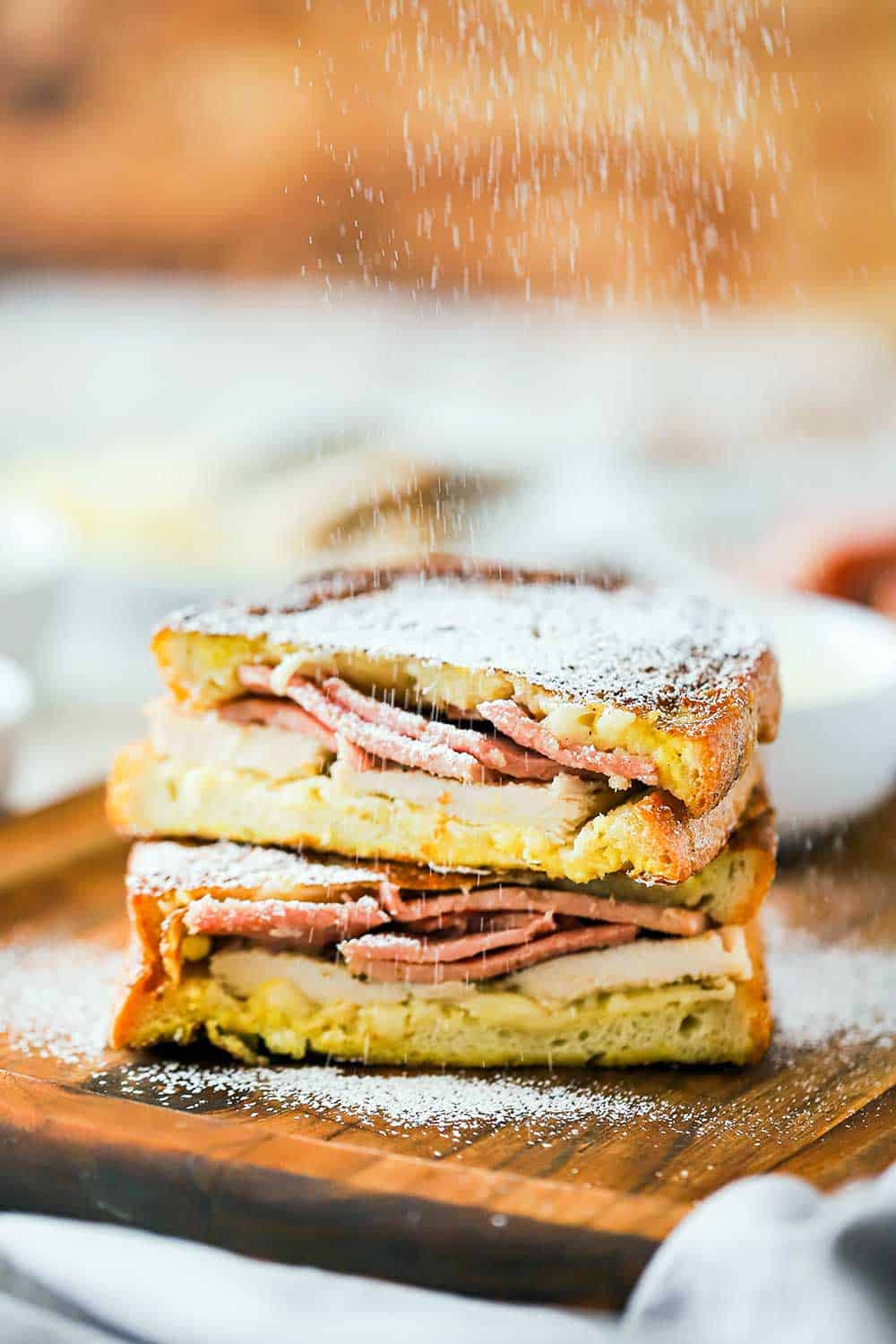 A Monte Cristo sandwich that is cut in half and stacked and powdered sugar sprinkling 