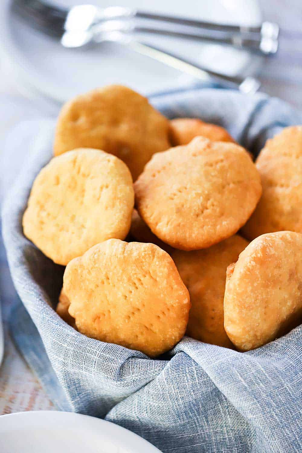 A basket lined with a grey napkin and filled with fried Caribbean Johnny Cakes.