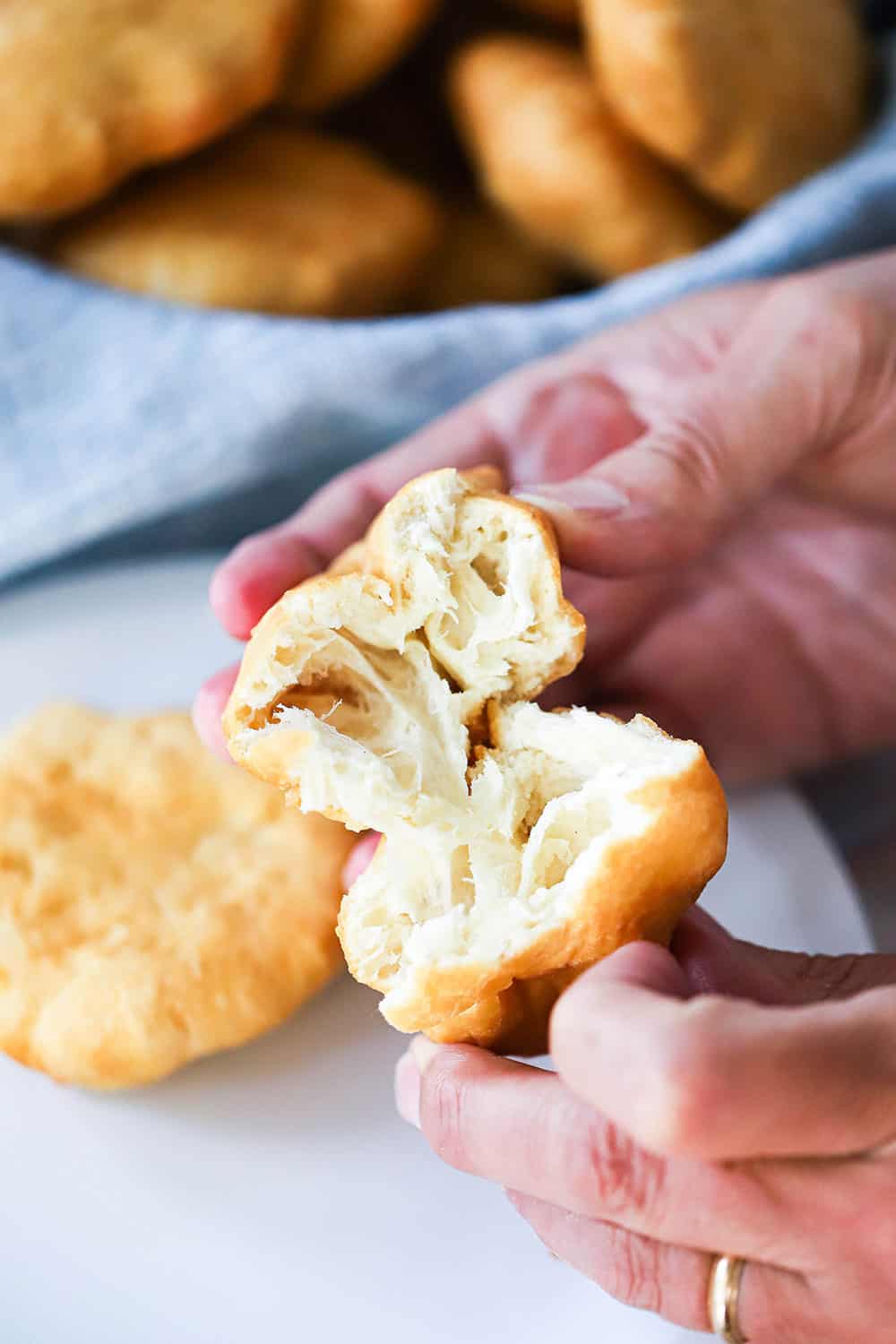 A person using two hands to pull apart a fresh Johnny cake. 