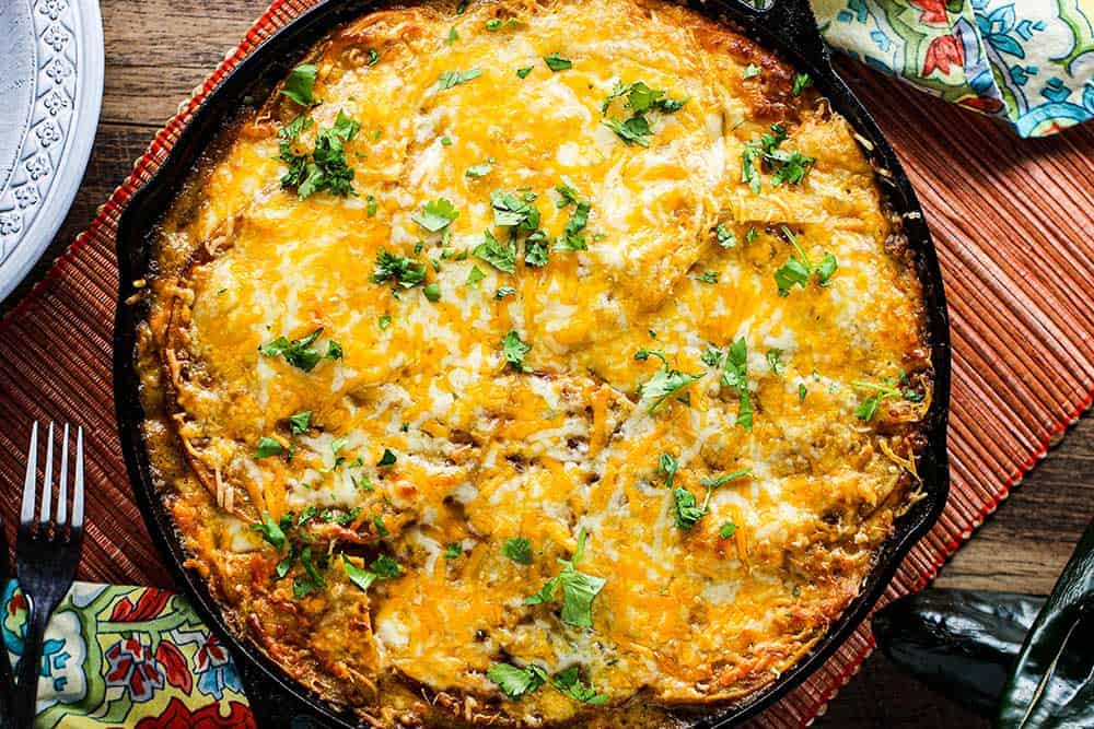 A large cast iron skillet of King Ranch Chicken Casserole next to festive napkins