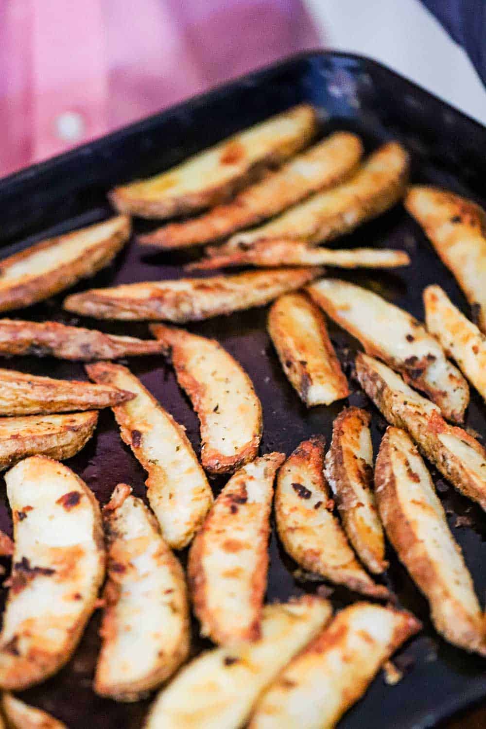 A baking sheet filled with potato wedges that have been roasted.