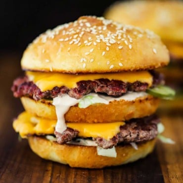 A homemade Big Mac sitting on a wooden cutting board.