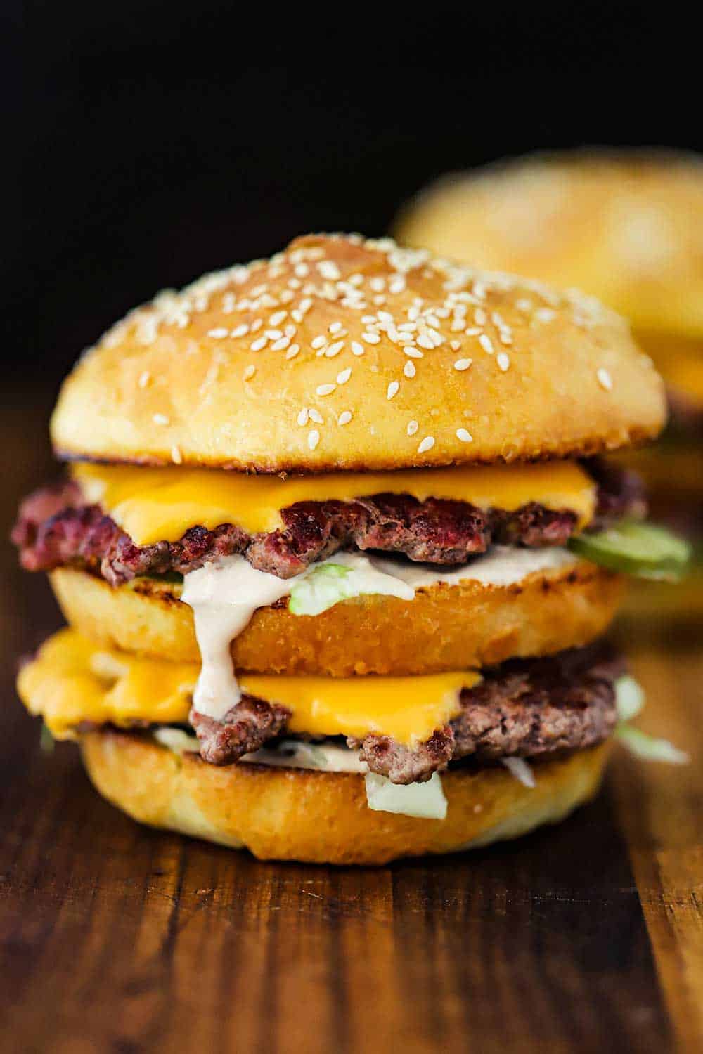 A homemade Big Mac sitting on a wooden cutting board.