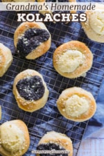 An overhead view of poppyseed and cream cheese filled kolaches sitting on a baking rack with a blue linen napkin underneath it.