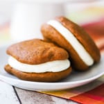 Two pumpkin whoopie pies sitting on a white dessert plate.