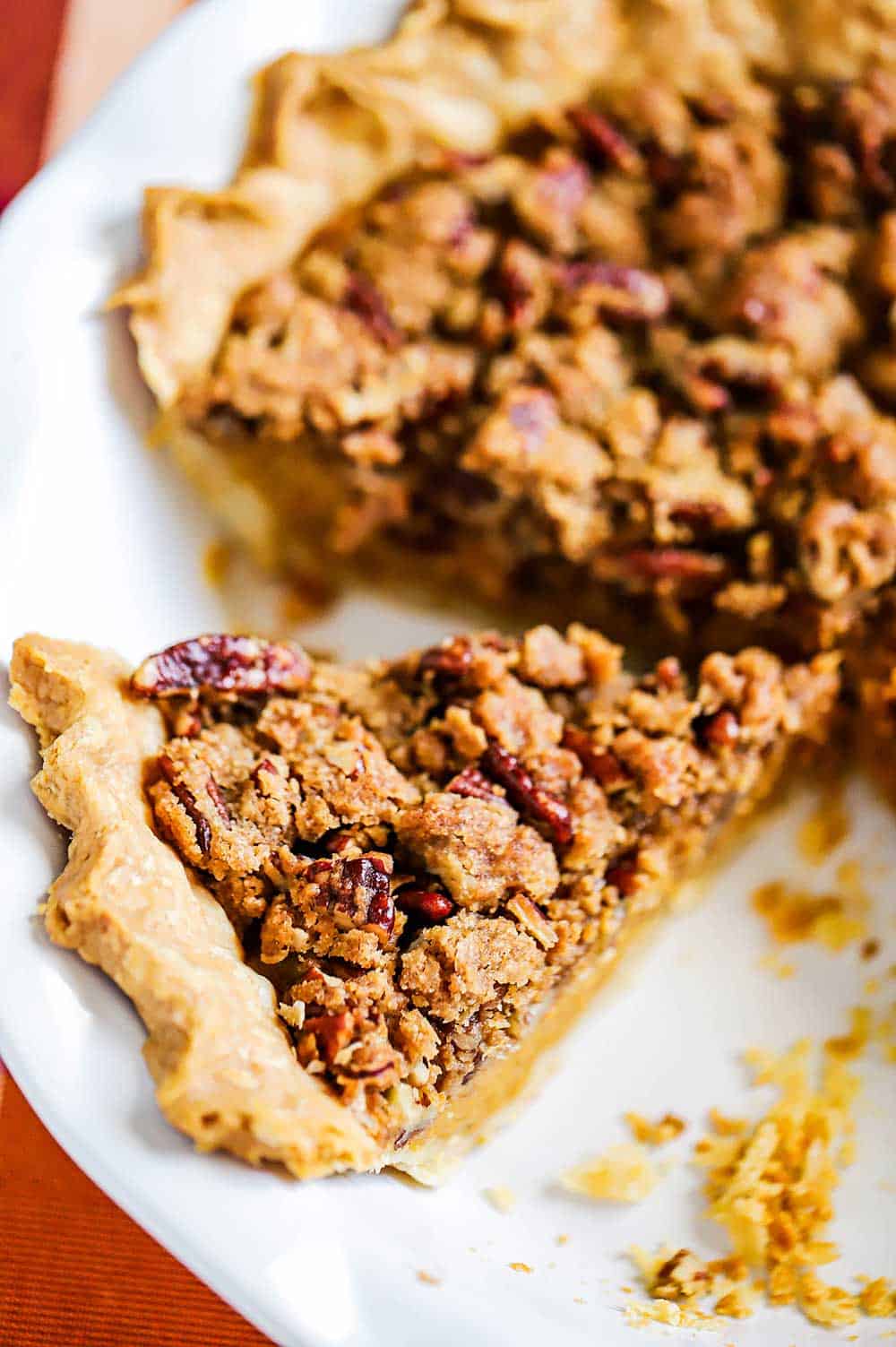 A slice of a sweet potato pie that is sitting next to the full pie in the pie dish. 