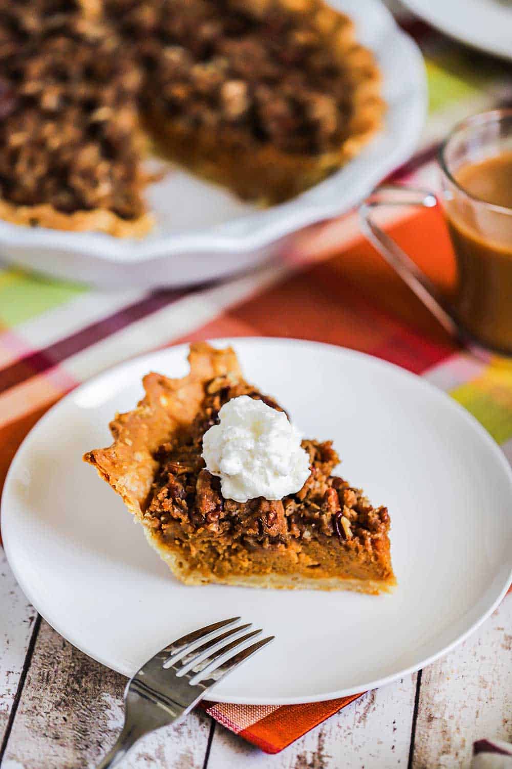 A slice of sweet potato pie sitting on a white dessert plate next to the pie in a pie dish. 