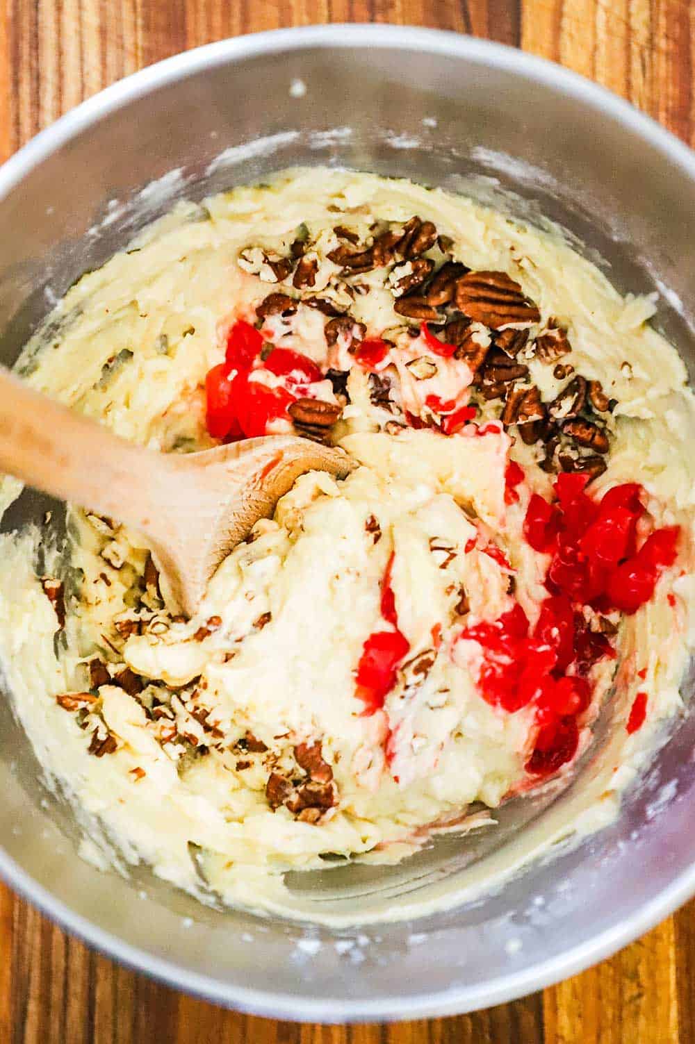 The batter for banana nut bread in a mixing bowl with a wooden spoon inserted into the middle. 