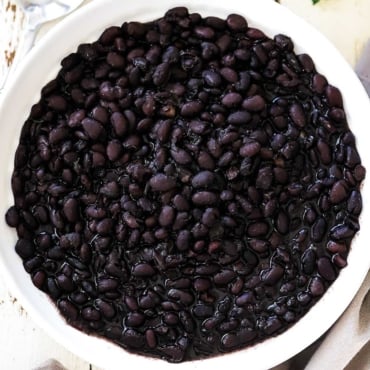 A circular white bowl filled with Mexican black beans.