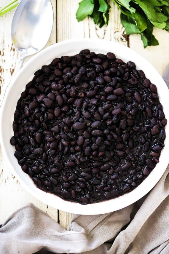 A circular white bowl filled with Mexican black beans.