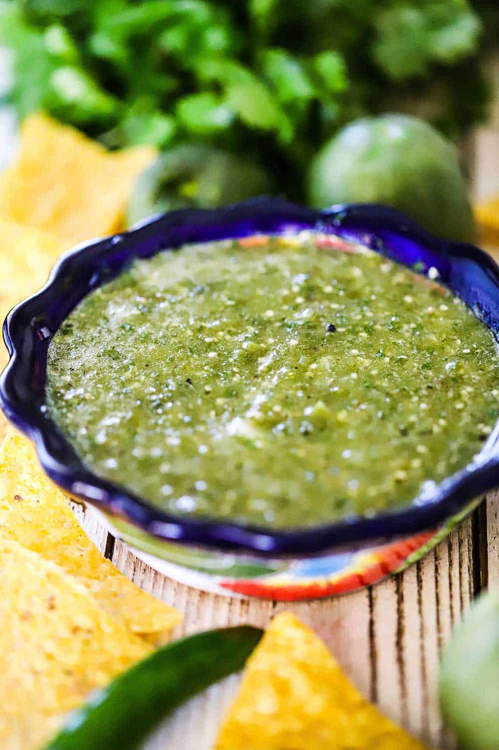 A festive bowl filled with salsa verde and surrounded by corn tortilla chips.