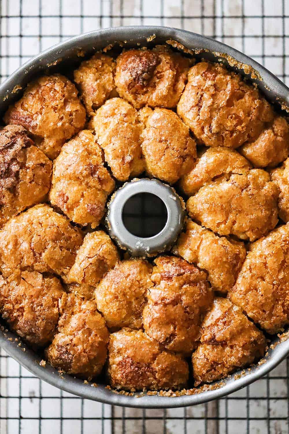 A bundt pan filled with cooked monkey bread sitting on a baking rack.