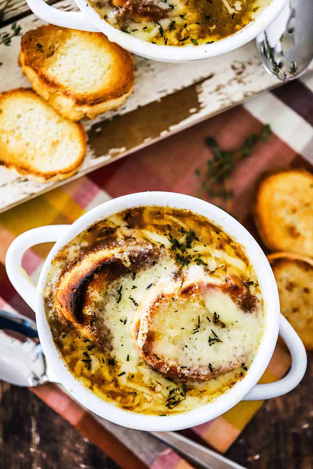 Two white bowls filled with French onion soup and topped with toasted bread slices and melted cheese.
