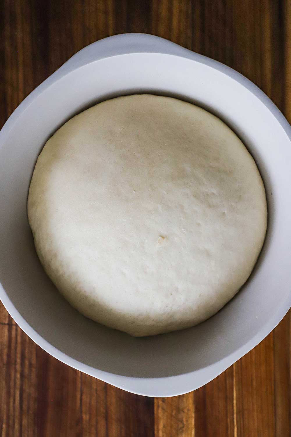 A large ceramic bowl filled with risen bread dough.