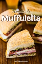 Four quarter pieces of a muffuletta sandwich sitting on a wooden cutting board.