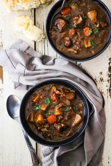 Two side-by-side blue soup bowls filled with slow-cooker beef stew.