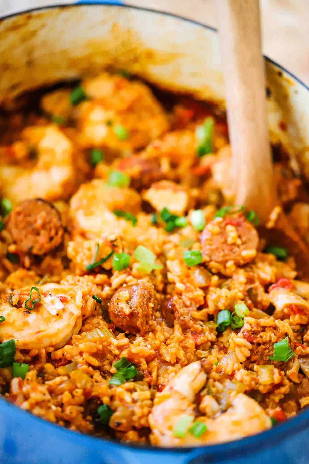 A blue Dutch oven filled with jambalaya with shrimp, sausage, and chicken.