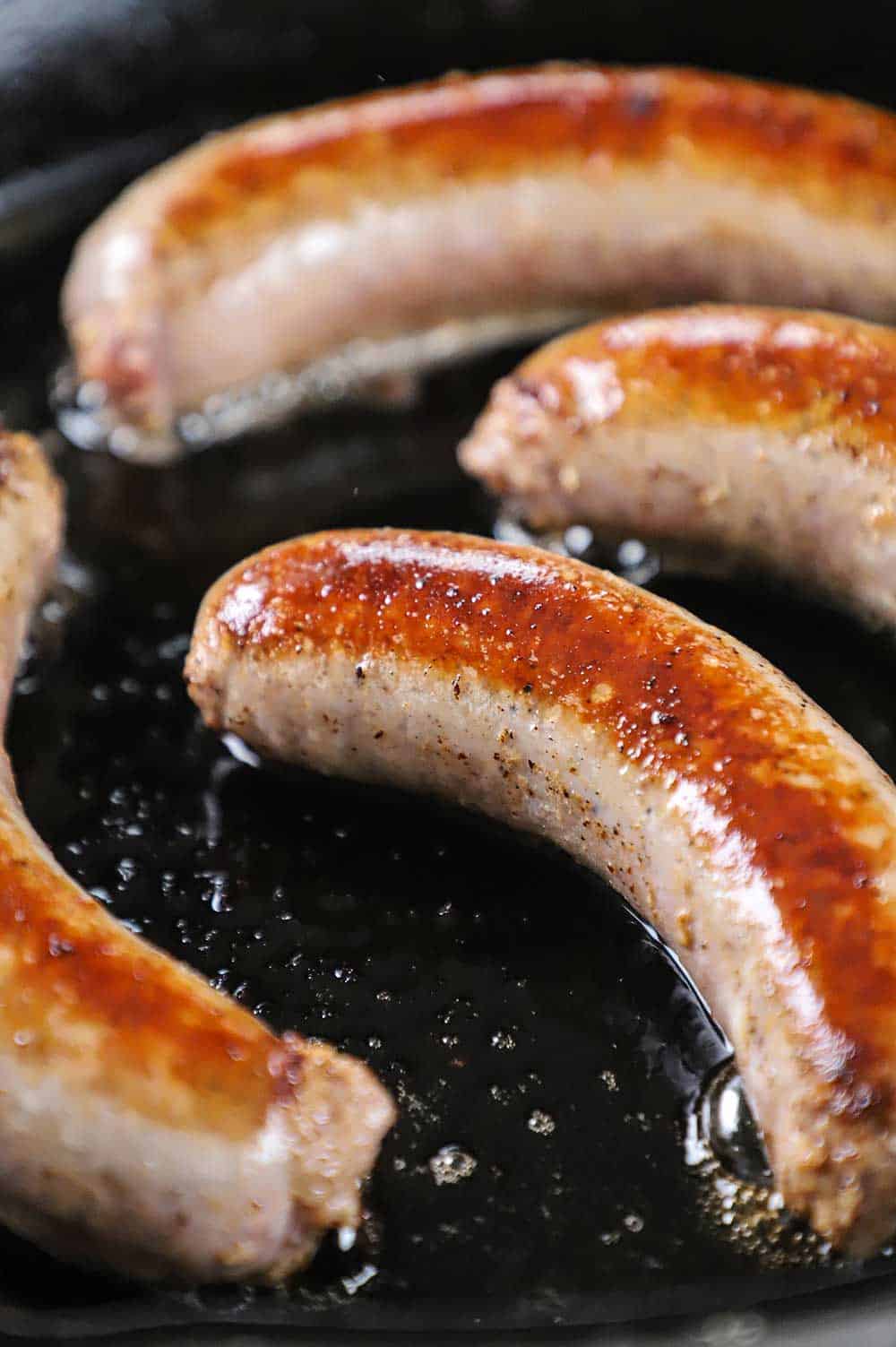 A cast-iron skillet filled with browned links of sausage in it.
