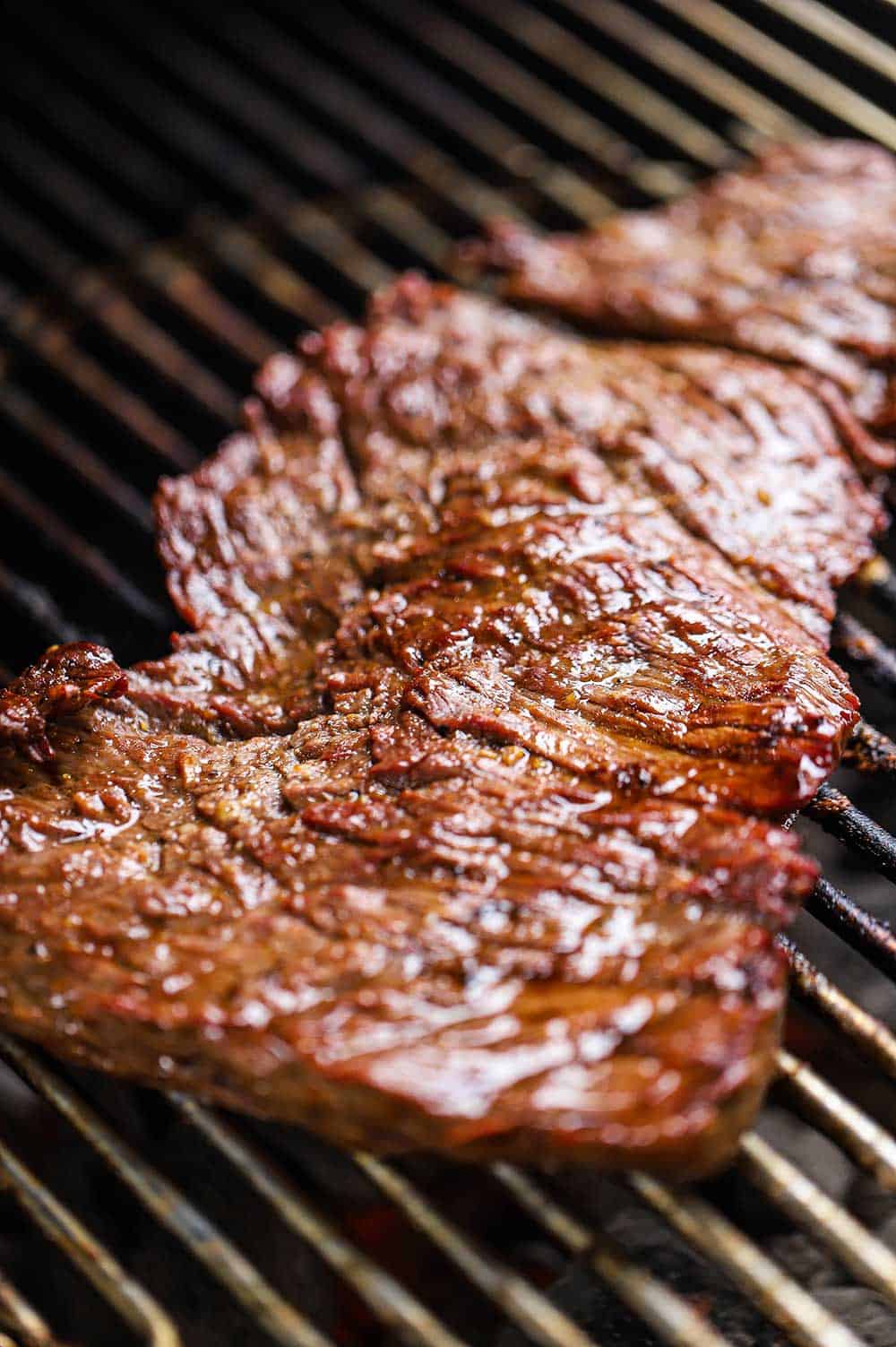 A seasoned flap steak on a charcoal grill.