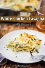 A white plate holding a serving of a white chicken lasagna with spinach with a bite taken out.