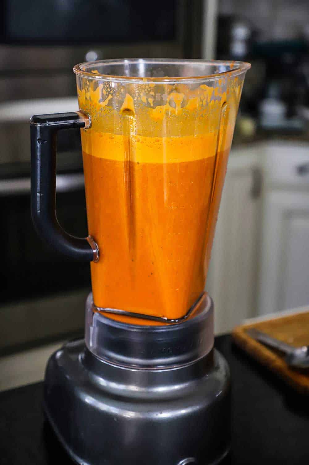 An electric blender filed with fresh carrot and ginger juice.