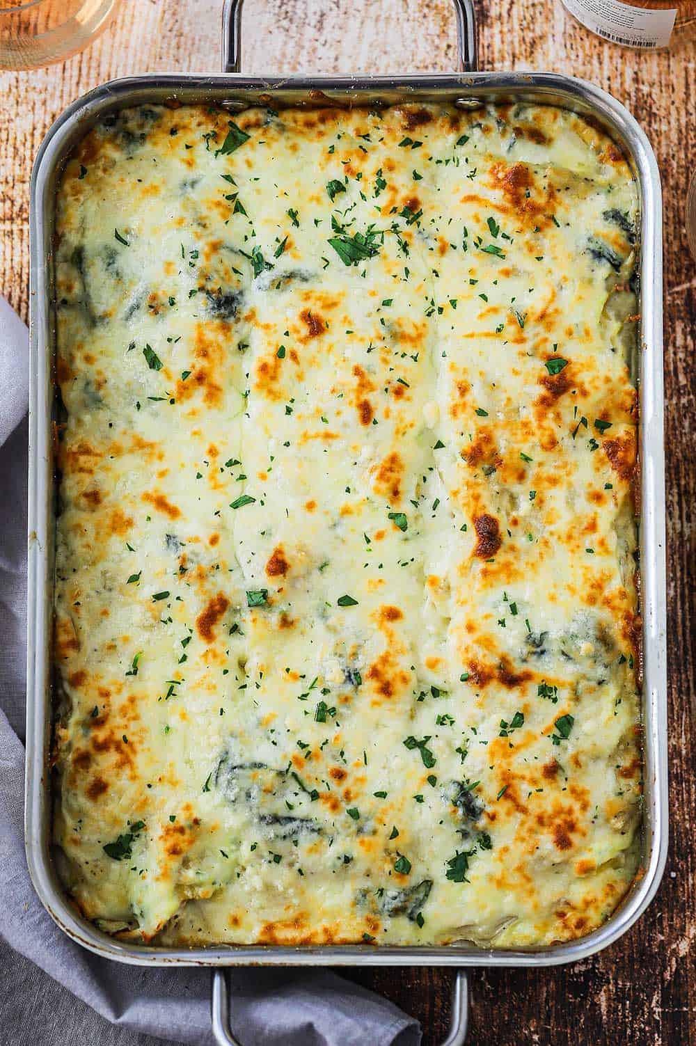 An overhead view of white chicken lasagna with spinach that has been fully cooked and lightly browned on top.