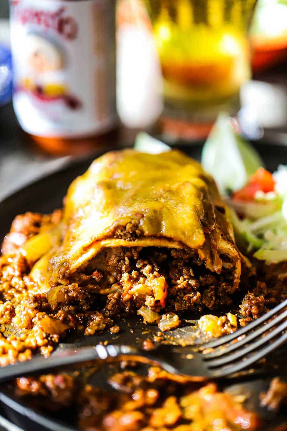 A smothered beef burrito that has been cut open with the meat and bean mixture spilling out.